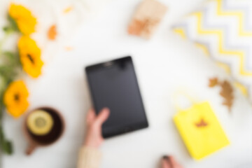 Blurred autumn background. Cozy home concept. Autumn flat lay with female hands holding tablet