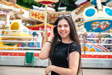 Happy young woman at amusement park on a sunny day. Happy summer days, travel and vacation concept