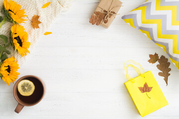 Autumn flat lay with empty space in center, tea, sunflowers and gift in cozy home