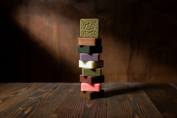 Stack of  traditional syrian olive and laurel soap bars with different scents, herbs  and colors on a dark wooden backround.
