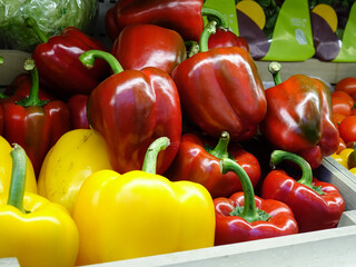 Containers with fresh vegetables in the store, red and yellow bell peppers, background
