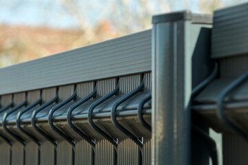 Modern metal fence with interlocking bars and a sleek top rail, showcasing durable construction, security, and contemporary design in close detail.