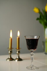 vertical photo Shabbat scene with two lit Sabbath candles in silver candlesticks, a glass of red wine. Shabbat Shalom