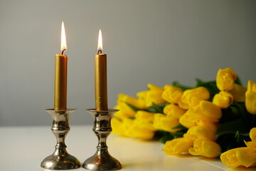Shabbat Candles with yellow tulips. Jewish Tradition and Peaceful Home Atmosphere. Shabbat Shalom