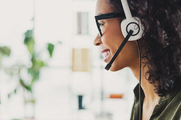 Professional businesswoman in an office setting speaking with a headset, representing customer...