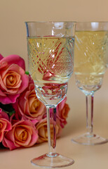 Horizontal photo of two glasses and a bouquet of roses on a light background, romantic setting, side view