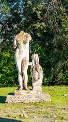 Headless ruins of ancient marble statue decorating a garden in Italy