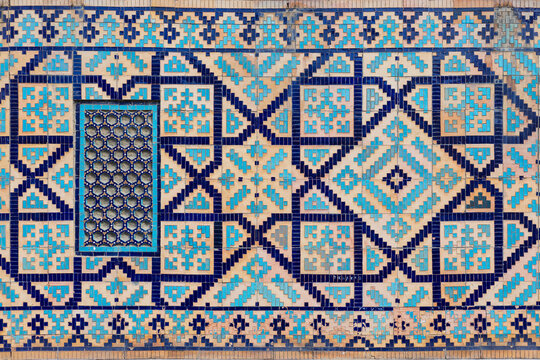 Background with traditional uzbek geometric ornament from blue ceramic tile. Earthenware mosaic pattern on clay wall. Culture heritage