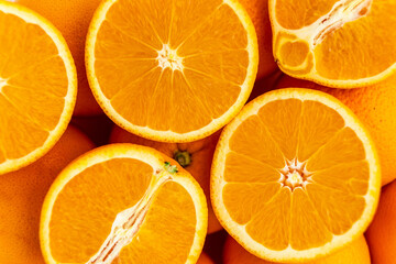 many oranges, some whole, some halved. food texture, orange fruit pattern, background of oranges