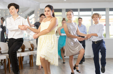 Fototapeta premium Happy teenage boys and beautiful girls dance a fiery twist dance