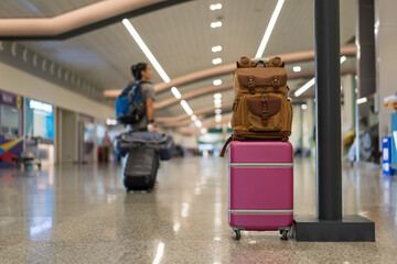 travel with pink luggage and brown backpack or camera bag to baggage in airport with blur asian people tourist dragging suitcase and carrying bags on holiday to journey in terminal for summer vacation © kornnphoto