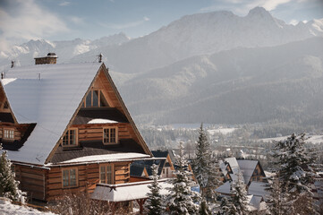 Snow covered wooden house with a view of the Tatra mountains in winter. Zakopane Poland.