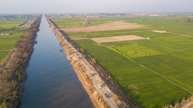 Aerial view of brb canal surrounded by lush fields and a tranquil road, Lahore, Punjab, Pakistan.