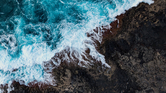 Aerial view of volcanic coast with crashing waves and rocky landscape, Lanzarote island, Canary Islands, Spain.