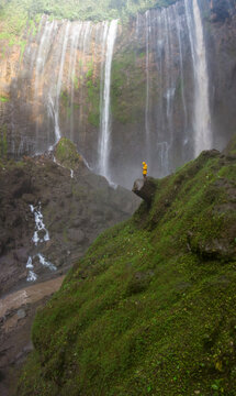 Aerial view of tumpak sewu waterfall cascading down lush green cliffs surrounded by a serene forest, Lumajang, East Java, Indonesia.