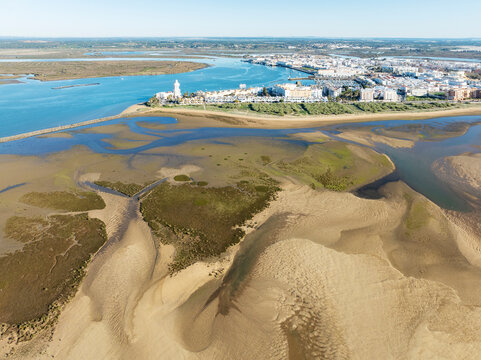 Aerial view of beautiful wetlands and a scenic town along a river with sandy shores and buildings, Isla Cristina, Huelva, Spain.