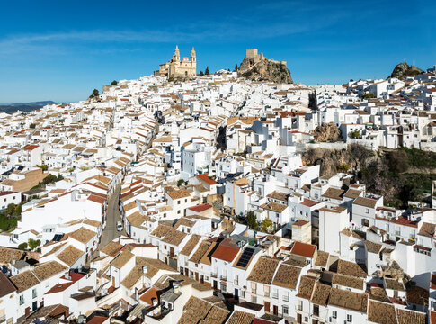 Aerial view of picturesque Olvera with whitewashed buildings, historic church, and castle on a hillside, Cadiz, Spain.