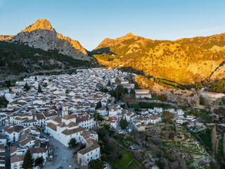 Aerial view of the historic village with stone buildings and rooftops nestled in the mountains at sunset, Grazalema, Cadiz, Spain.