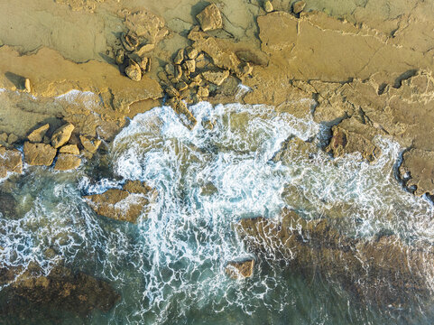 Aerial view of beautiful coastal beach with crashing waves and rocky shoreline, Trafalgar, Cadiz, Spain.