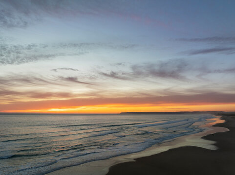 Aerial view of tranquil sunset over the Atlantic Ocean with beautiful beach and soft waves, Barbate, Cadiz, Spain.