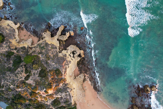 Aerial view of beautiful beach with cliff and rocks beside the ocean, Algave, Portugal.