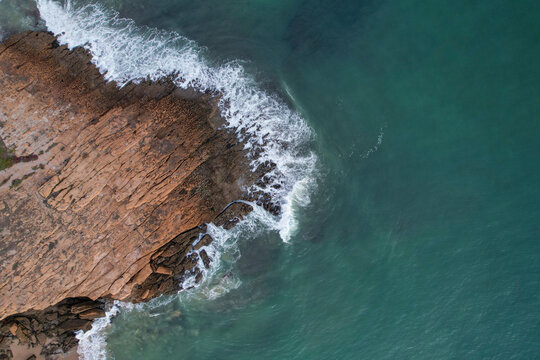 Aerial view of beautiful beach with rocky shoreline and waves, Algave, Portugal.