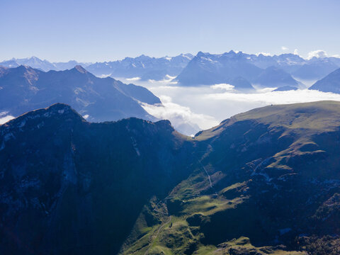 Aerial view of majestic mountains under a serene sky with picturesque clouds, Stoos, Schwyz, Switzerland.