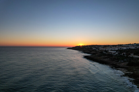 Aerial view of beautiful beach at sunset with calm waves and serene coastline, Algave, Portugal.