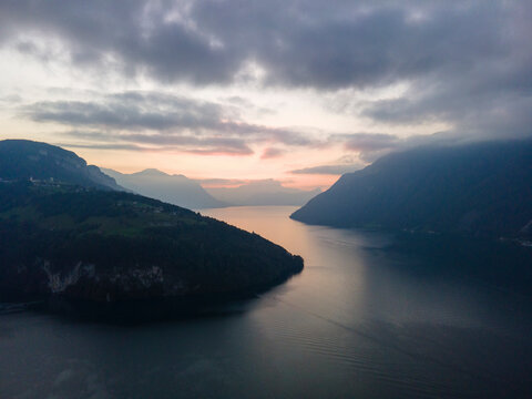 Aerial view of serene mountains and tranquil river at sunset with dramatic clouds, Stoos, Schwyz, Switzerland.