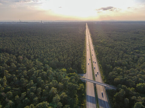 Aerial view of scenic autobahn surrounded by lush forest and trees at sunset, Mannheim, Baden Wuttermberg, Germany.