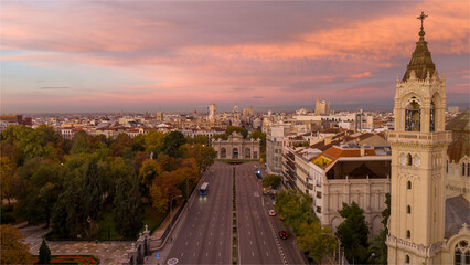 Aerial view of the beautiful Puerta de Alcala surrounded by elegant buildings and vibrant trees at sunset, Salamanca, Madrid, Spain.