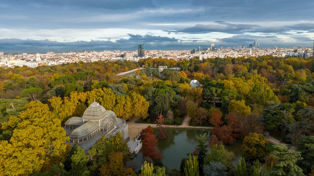 Aerial view of serene Retiro Park with vibrant autumn foliage, Crystal Palace, and tranquil pond, Madrid, Madrid, Spain. - Powered by Adobe