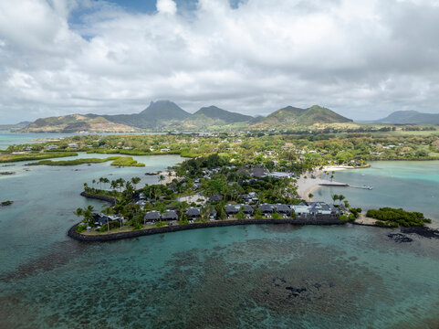 Aerial view of ilot lievres with beautiful white sand beach and turquoise lagoon surrounded by palm trees and scenic mountains, Flacq District, Mauritius.
