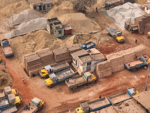 Aerial view of brick factory with yellow trucks and sand piles, Darus Salam Thana, Dhaka, Bangladesch.