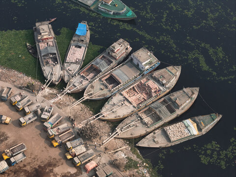 Aerial view of boats and brick factory along the river in an industrial area, Amin Bazar, Sabhar, Dhaka, Bangladesh.