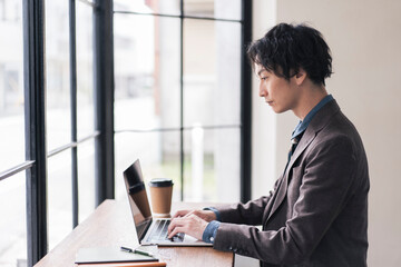 カフェでノートパソコンを開き仕事をしている男性。