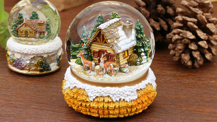 Snow globe featuring a cozy cabin with trees and deer  