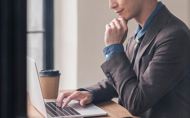 ノートパソコンを開き仕事をしている男性。