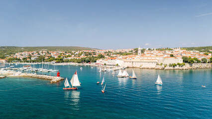 Aerial view of picturesque sailboats in a tranquil harbor with a scenic coastal town, Krk, Primorje-Gorski Kotar, Croatia.