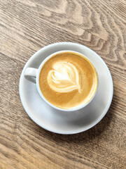 Cup of Cappuccino with Latte Art on Wooden Table in Cozy Cafe