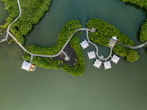 Aerial view of serene tropical island resort with wooden pathways and tents surrounded by lush greenery and tranquil lagoon, prince maurice, flacq, mauritius.