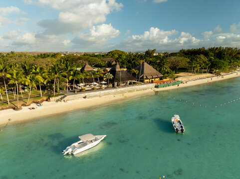 Aerial view of tranquil Trou aux Biches beach with clear blue ocean, palm trees, and boats, Triolet, Pamplemousses, Mauritius.