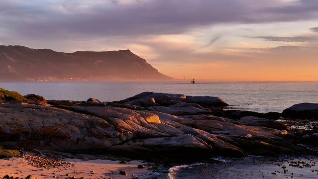 Aerial view of serene froggy pond at sunset with clouds and rocky shoreline, Simon's Town, Western Cape, South Africa.