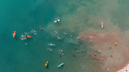 Aerial view of people kayaking and swimming in clear turquoise water with waves, Potrerillos, Mendoza, Argentina.