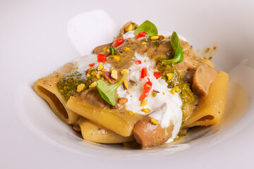 Paccheri con funghi, pesto di pistacchio e stracciata di bufala serviti in un ristorante come primo piatto
