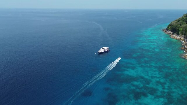 Drone aerial shot of Similan Islands in the Andaman Sea in Thailand with liveaboard scuba diving boats in the bay surrounded by beautiful tropical blue water and rocky island with jungle and waves