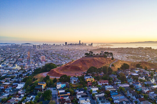 Aerial view of beautiful skyline and homes atop hills with trees at sunset, Bernal Heights, California, United States.