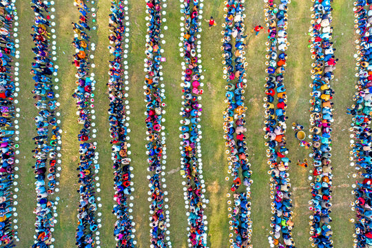 Aerial view of vibrant community gathering with plates arranged in rows on grass, Saidpur, Rajshahi, Bangladesh.