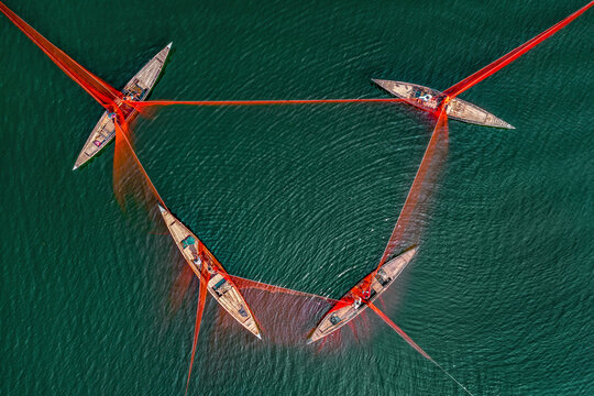 Aerial view of fishermen using a huge net on a river with traditional boats, Sariakandi, Rajshahi, Bangladesh.