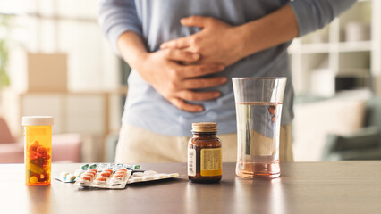 Woman with stomach ache with pills on the table in front of her